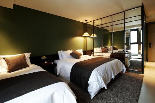 a hotel room with two beds and a mirror at Urban Boutique Hotel in Anyang