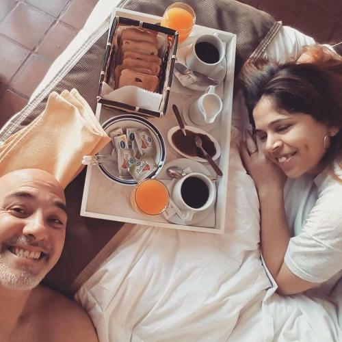 a man and a woman laying in bed with a tray of breakfast at GM Rooms Boutique Hotel in La Rioja