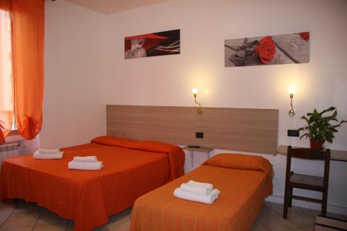 2 letti in una camera con lenzuola arancioni di Hotel Adelchi a Milano