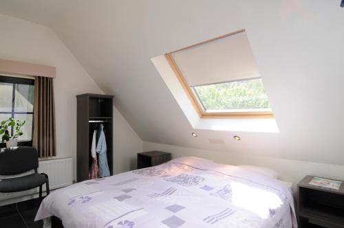 - une chambre mansardée avec un lit et une fenêtre dans l'établissement Vakantiewoning Zavelbos, à Maaseik
