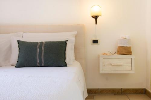 a white bed with a green pillow and a nightstand at Le Gioie - Villa Macchia Mediterranea - Splendida villa vista mare immersa nel verde in Torre Pali 