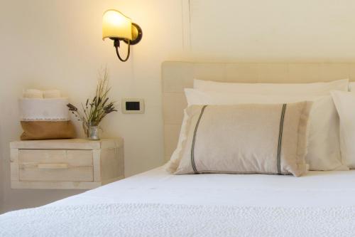 a bedroom with a white bed with a lamp on a night stand at Le Gioie - Villa Macchia Mediterranea - Splendida villa vista mare immersa nel verde in Torre Pali 