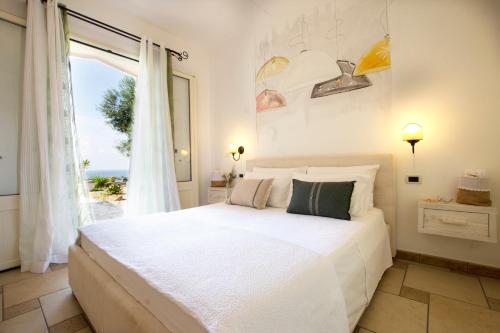 a bedroom with a large white bed and a window at Le Gioie - Villa Macchia Mediterranea - Splendida villa vista mare immersa nel verde in Torre Pali 