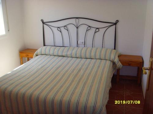een bed met een gestreepte sprei en een houten tafel bij RIVIERA in L'Ametlla de Mar