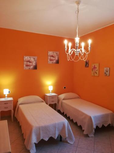 two beds in a room with orange walls at GIARDINO DI PRIMAVERA in Bagnoregio