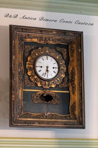 an ornate clock in a frame on a wall at Antica Dimora Conti Custoza in Roverbella