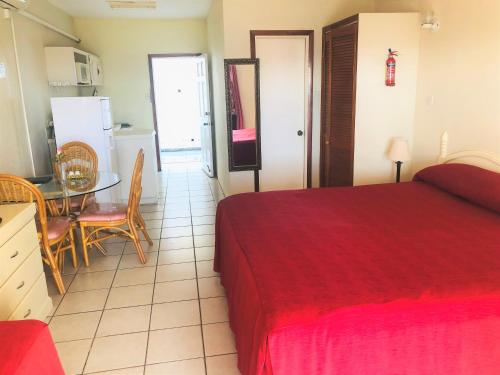a bedroom with a bed and a table and a kitchen at Rosewood Apartment Hotel in Arnos Vale
