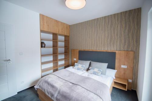 a bedroom with a large bed with a wooden headboard at ff apartments Jasná Lúčky in Demanovska Dolina