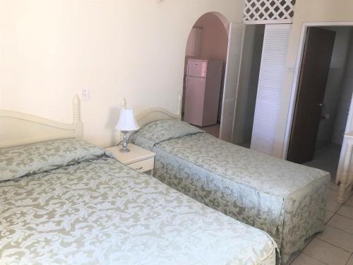 a bedroom with two beds and a lamp on a table at Rosewood Apartment Hotel in Arnos Vale