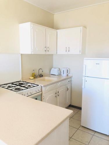 a kitchen with white cabinets and a white refrigerator at Rosewood Apartment Hotel in Arnos Vale