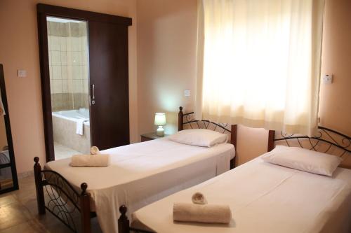two beds in a room with a bathroom with a tub at Starlit Villa in Kathikas