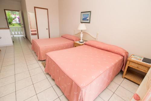 a room with two beds with pink sheets at Rosewood Apartment Hotel in Arnos Vale