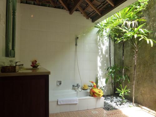 a bathroom with a bath tub with a palm tree at Gazebo Beach Hotel in Sanur