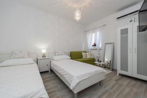 a white bedroom with two beds and a green couch at Apartment Maja in Novalja in Novalja