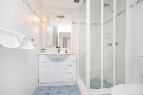 a white bathroom with a shower and a sink at Spindrift on the Beach - Absolute Beachfront in Gold Coast