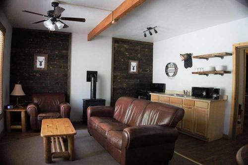 a living room with a leather couch and a table at Shaver Lake Village Hotel in Shaver Lake