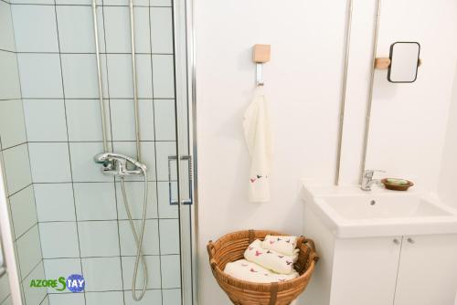 een badkamer met een douche en een mand met handdoeken bij AZORESTAY in Horta