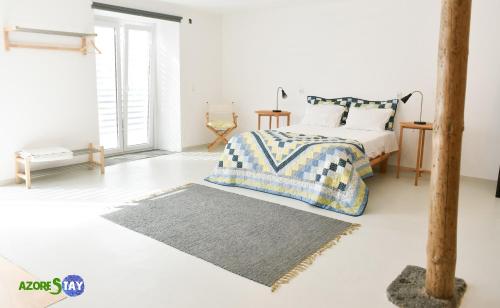 een witte slaapkamer met een bed en een tapijt bij AZORESTAY in Horta
