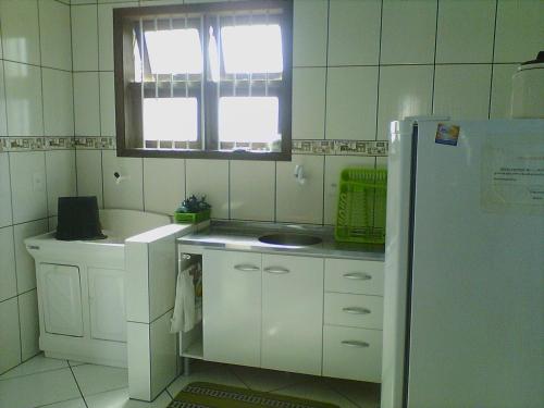 cocina con nevera blanca y ventana en Aluguel de Verão, en Torres
