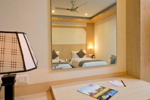 a hotel room with a bed and a mirror at Hotel Southern Grand in Vijayawāda