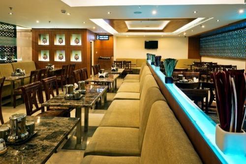 un restaurante con mesas y sillas y un sofá largo en Hotel Southern Grand, en Vijayawāda
