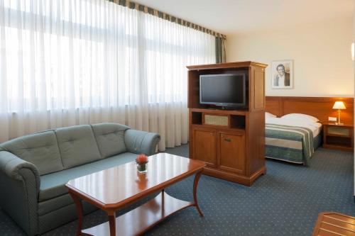 a hotel room with a couch and a tv and a bed at Hollywood Media Hotel am Kurfürstendamm in Berlin