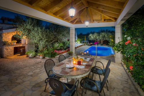 eine Terrasse mit einem Tisch, Stühlen und einem Pool in der Unterkunft New modern dream villa 2019 in Kreševo