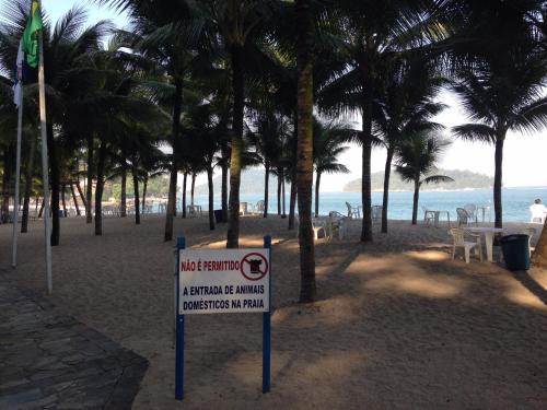 a no swimming sign on a beach with palm trees at Porto Real Resort Suites Angra in Mangaratiba