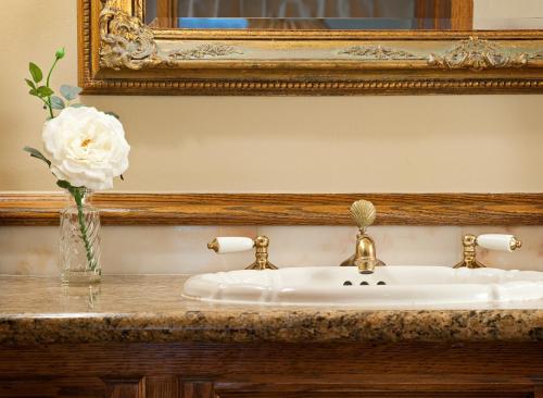 a bathroom sink with a flower in a vase on a counter at Doryman's Oceanfront Inn in Newport Beach