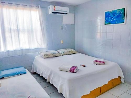 a room with a large white bed with pillows on it at Casa à beira-mar, piscina in Pitimbu