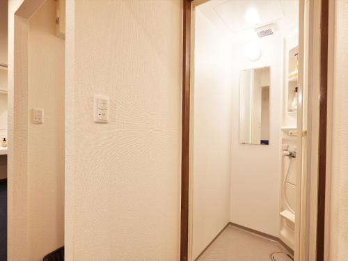 a door leading into a room with a refrigerator at Creass Hotel Tsubogawa Marche in Naha