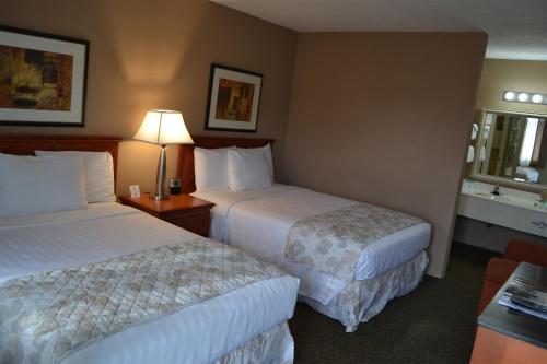 a hotel room with two beds and a table with a lamp at Cascades Inn in Bloomington
