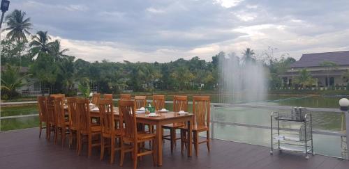 a wooden table and chairs on a deck with a fountain at Lamphurai Riverside Resort and Spa in Trat