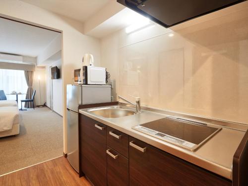 a kitchen with a sink and a microwave at Creass Hotel Tsubogawa Marche in Naha