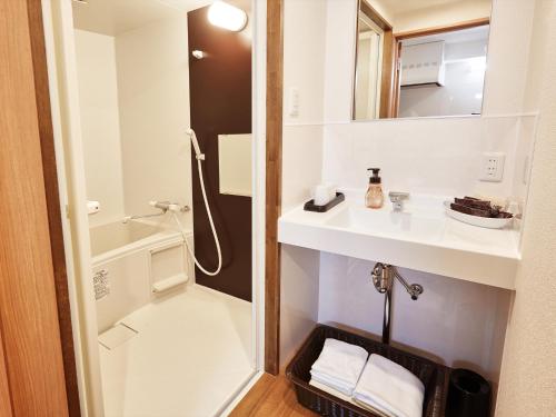 a bathroom with a sink and a shower at Creass Hotel Tsubogawa Marche in Naha