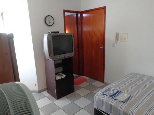 Habitación con TV, cama y puerta en FARO FINO 104 DISNEY, en Goiânia