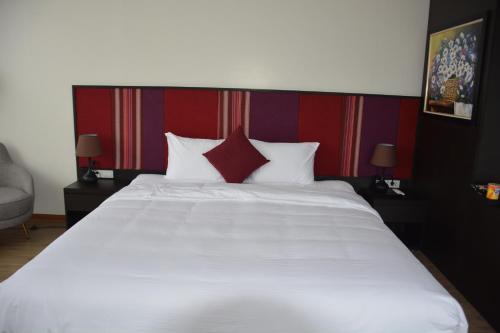 a bedroom with a large white bed with red pillows at Max Boutique Hotel in Cao Bằng