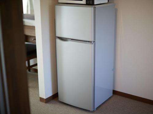 a white refrigerator in the corner of a room at Creass Hotel Tsubogawa Marche in Naha