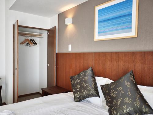 a hotel room with a bed and a picture on the wall at Creass Hotel Tsubogawa Marche in Naha