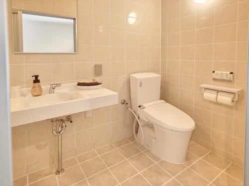 a bathroom with a toilet and a sink at Creass Hotel Tsubogawa Marche in Naha