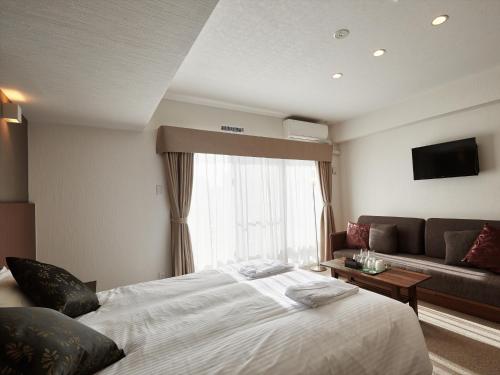 a hotel room with a bed and a couch at Creass Hotel Tsubogawa Marche in Naha