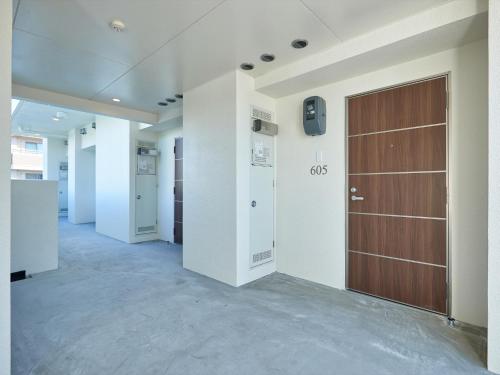 a hallway with a brown door in a building at Creass Hotel Tsubogawa Marche in Naha