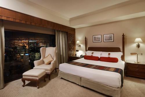 a hotel room with a large bed and a chair at The Davis Bangkok in Bangkok