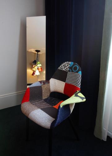a chair with a blanket on it in front of a mirror at Hotel le Cinq Hyper - Centre in Chambéry