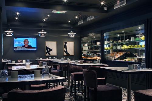 a dining room with tables and chairs and a tv at Hotel le Cinq Hyper - Centre in Chambéry