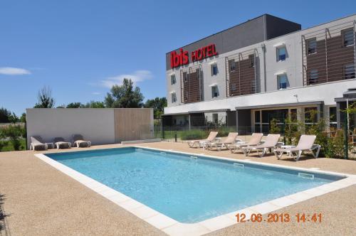 a swimming pool in front of a building at ibis Istres Trigance in Istres