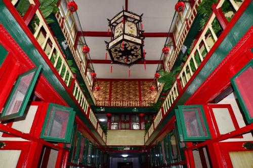 a hallway with red doors and a chandelier in a building at Qianmen Courtyard Hotel in Beijing