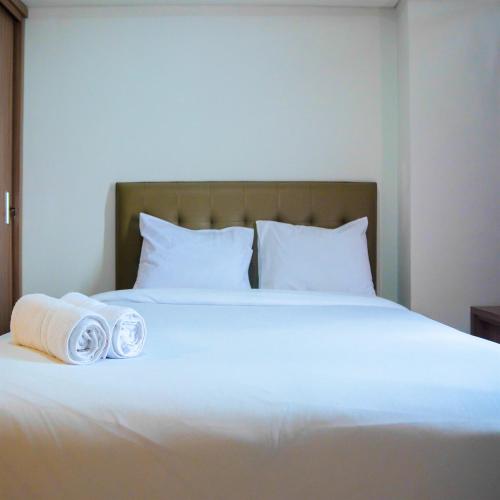 a white bed with two rolled towels on it at Cozy 1BR Apartment H Residence near MT Haryono By Travelio in Jakarta