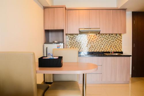 a kitchen with a wooden table and a refrigerator at Cozy 1BR Apartment H Residence near MT Haryono By Travelio in Jakarta