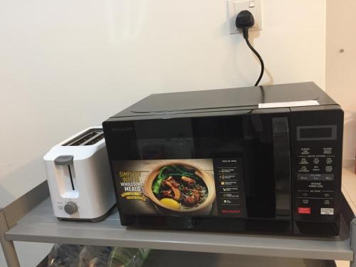 a microwave oven sitting on a shelf with a toaster at Emira Residence Sek 13 Shah Alam Wi-Fi Netflix in Shah Alam